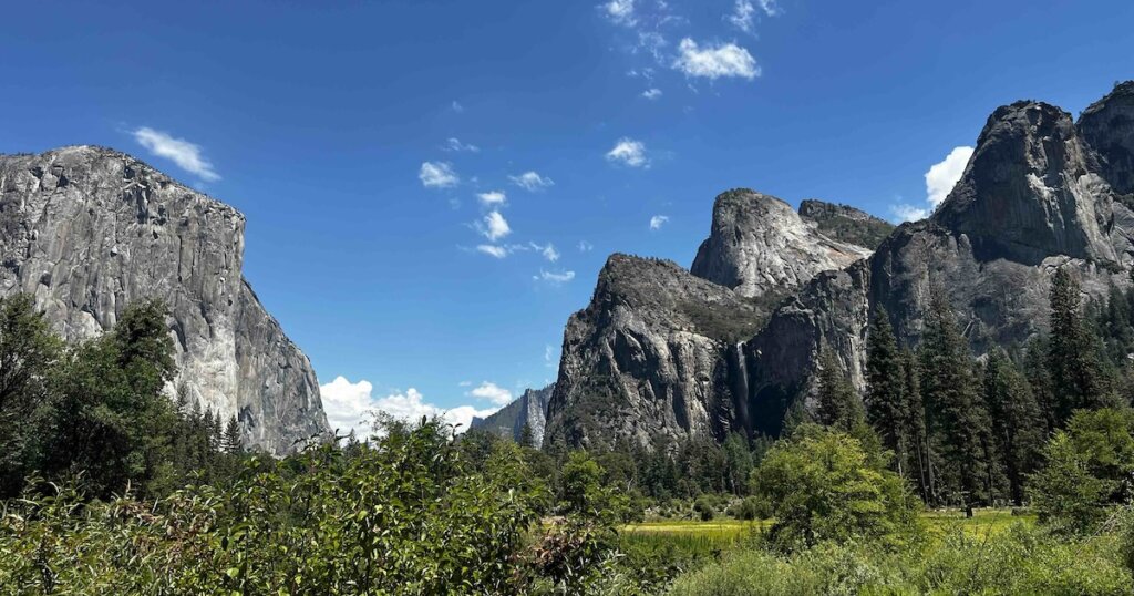 Panoramic view of green trees and towering granite cliffs in Yosemite valley, practicing mindfulness in nature.